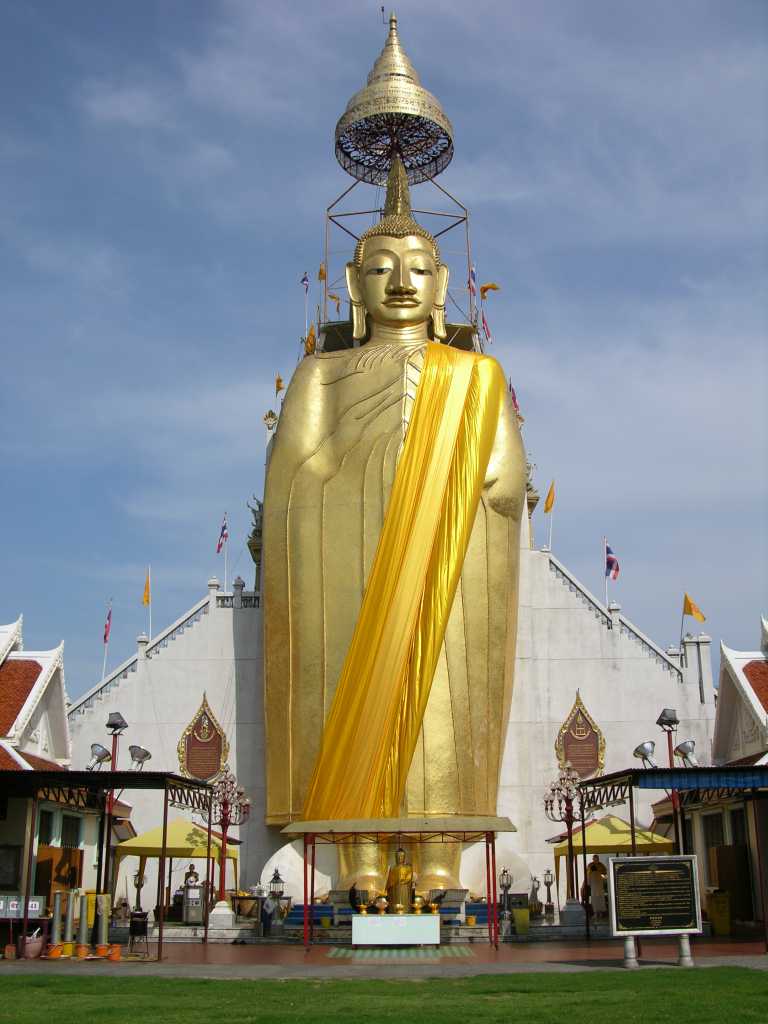 Bangkok 02 01 Luang Pho To Buddha Statue We met a nice man on the way to the Grand Palace, who told us it was closed this morning. Although I had read of this scam, I was feeling great and compassionate and wanted to see how it played out. He mentioned that he could get us a private tuk-tuk tour to show us around some of the Bangkok sights for only a hundred Baht. We took him up on his offer. As long as you are willing to say no to the shopping portion of the tour, its great fun indeed. Our first stop was at Luang Pho To, a gigantic 32m x 11m statue of Buddha, built starting in 1867, and covered in 24k golden mosaics. The topknot of the Buddha image supposedly contains a relic of Lord Buddha brought from Sri Lanka.